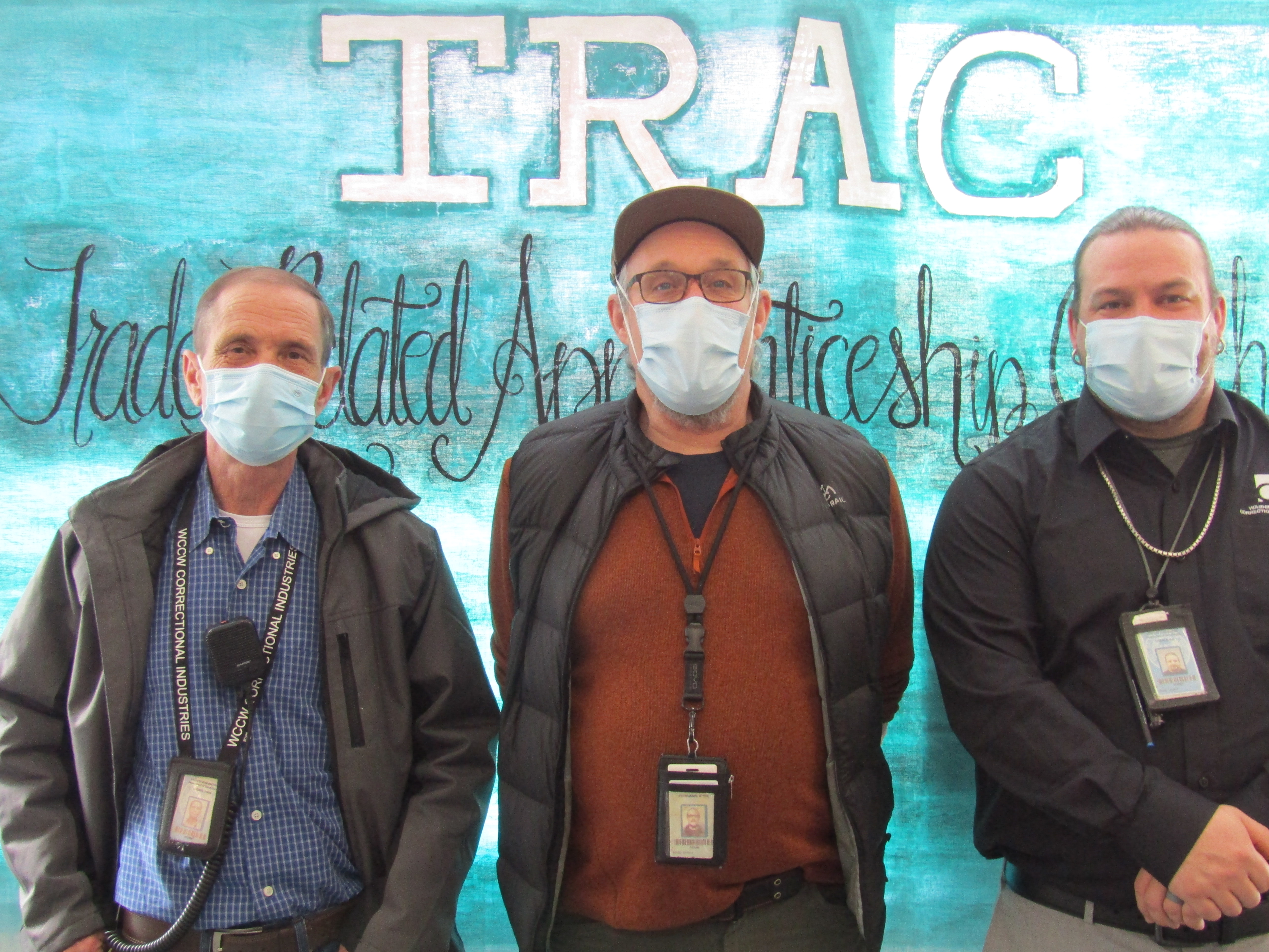 TRAC instructors pose in front of TRAC banner