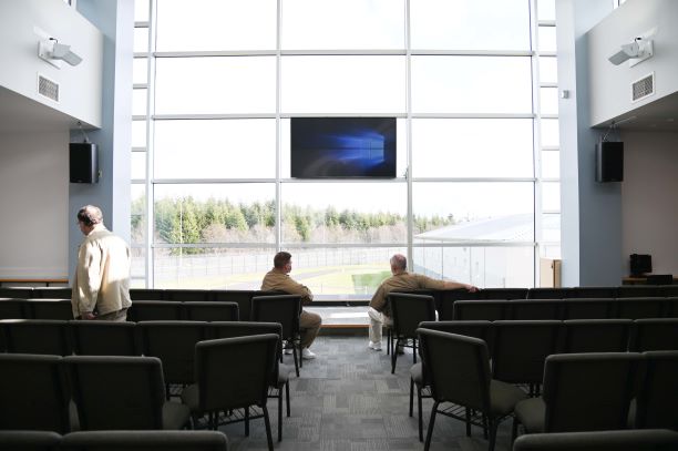 Two incarcerated individuals sitting in front row of chapel