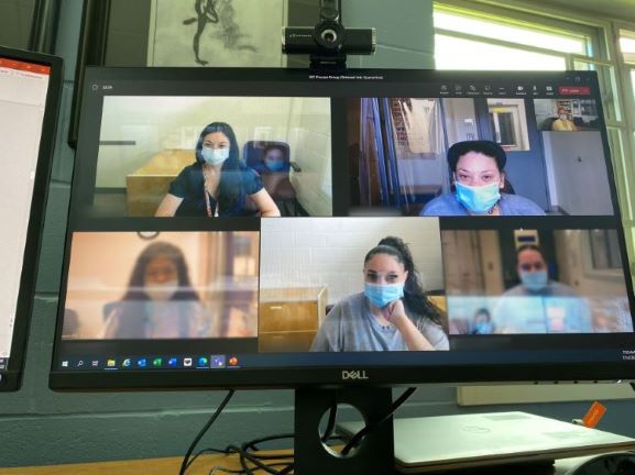 Computer screen with five people in a meeting