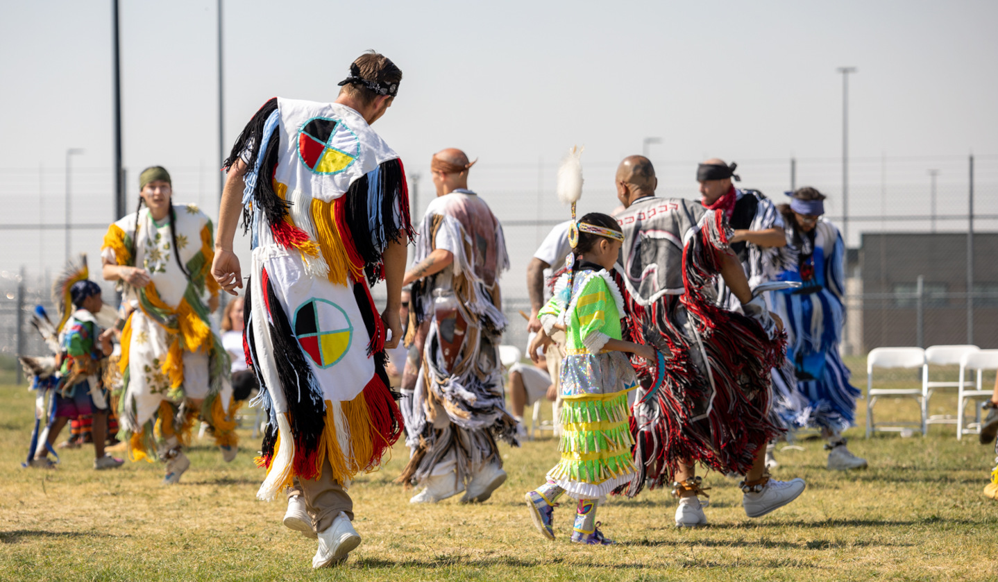 Group of indigenous people in regalia participating in ceremonial dance