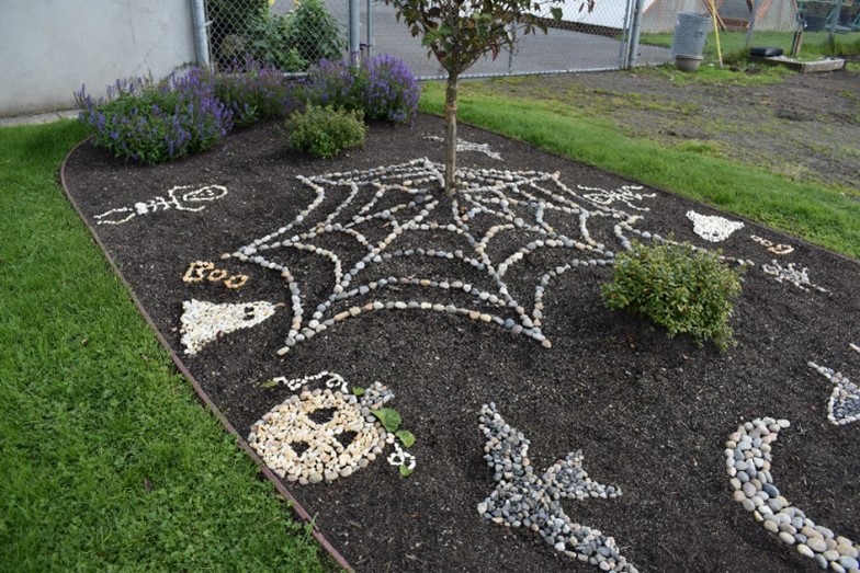 A garden featuring rocks depicting pumpkins, ghosts, bats, spider webs, and other fall-themed designs.