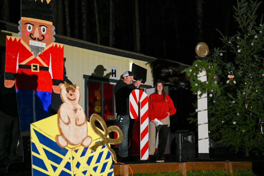 A man singing into a microphone surrounded by homemade Christmas decorations.