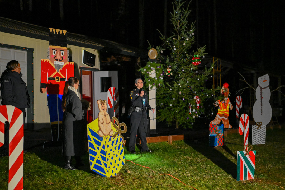 A woman talking into a microphone surrounded by Christmas decorations.