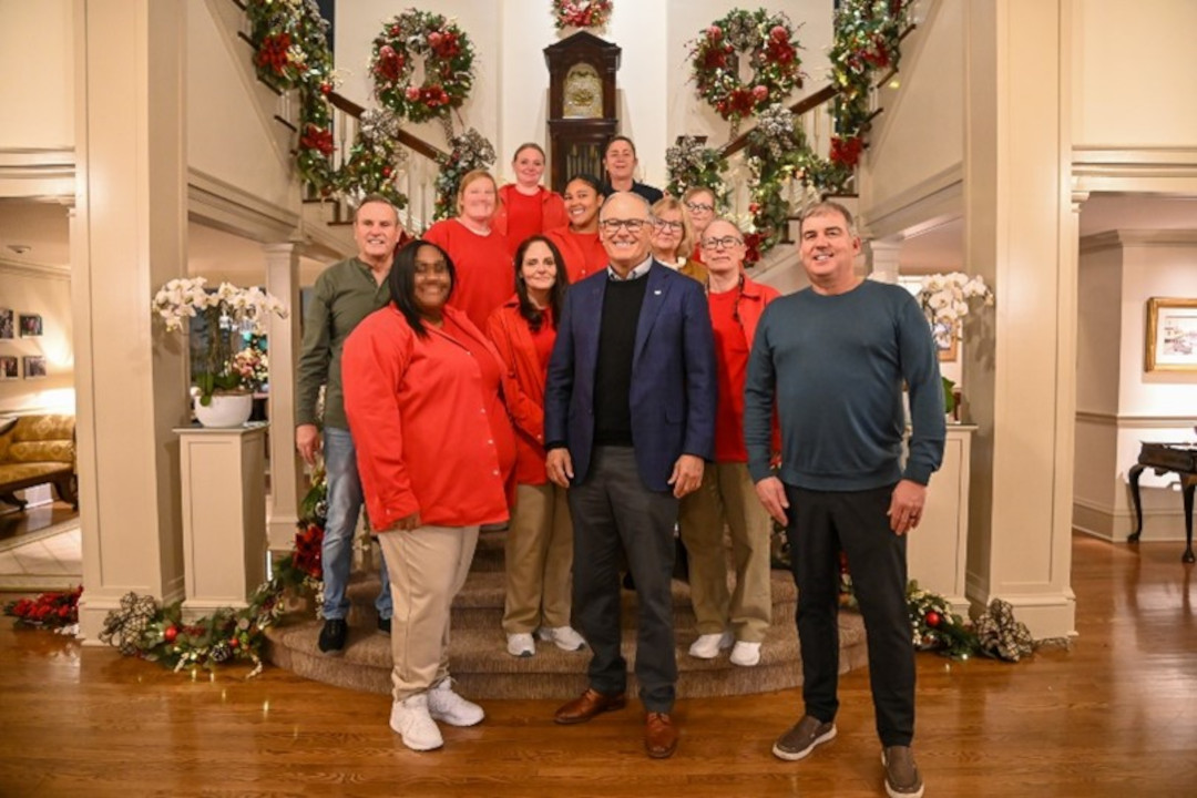 A group poses for a photo together in front of a decorated stairwell