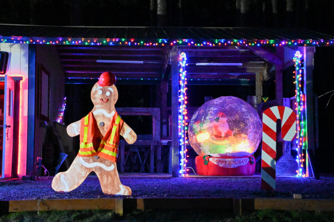 A gingerbread man wearing a safety vest next to an inflatable Santa Claus snow globe.