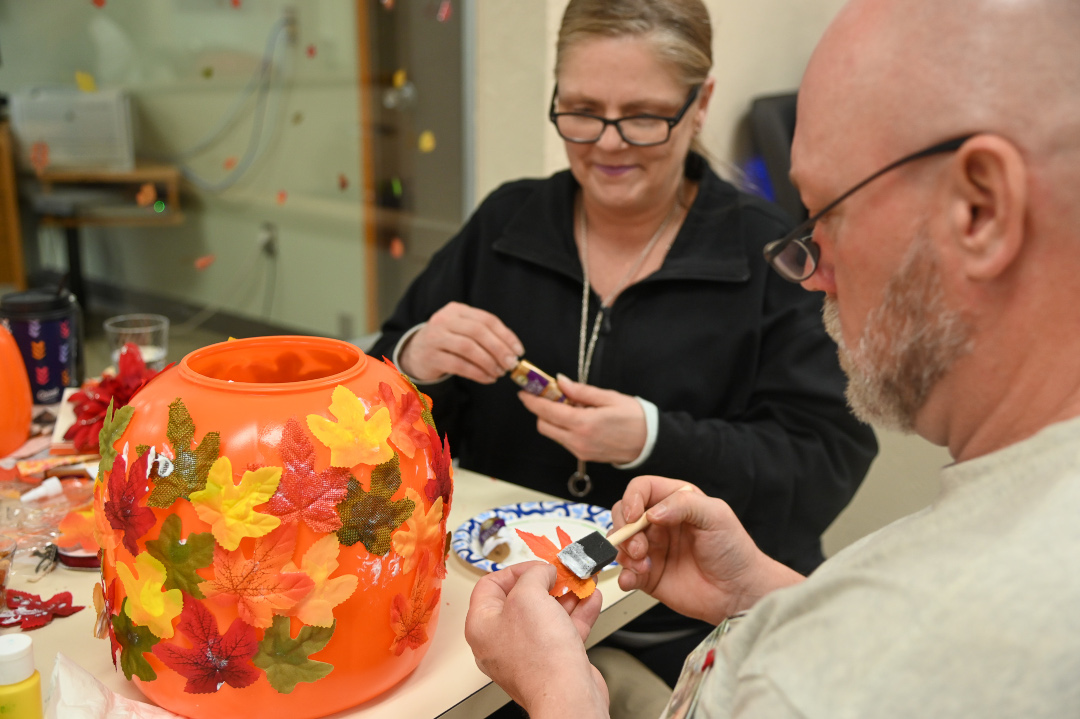 A man decorating a pumpkin.