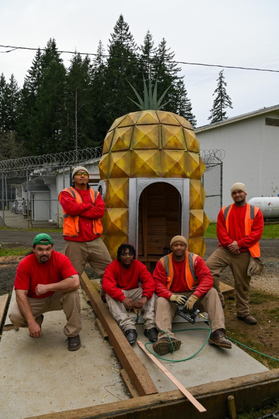 Group of me pose in front of a hand built wooden pineapple house.