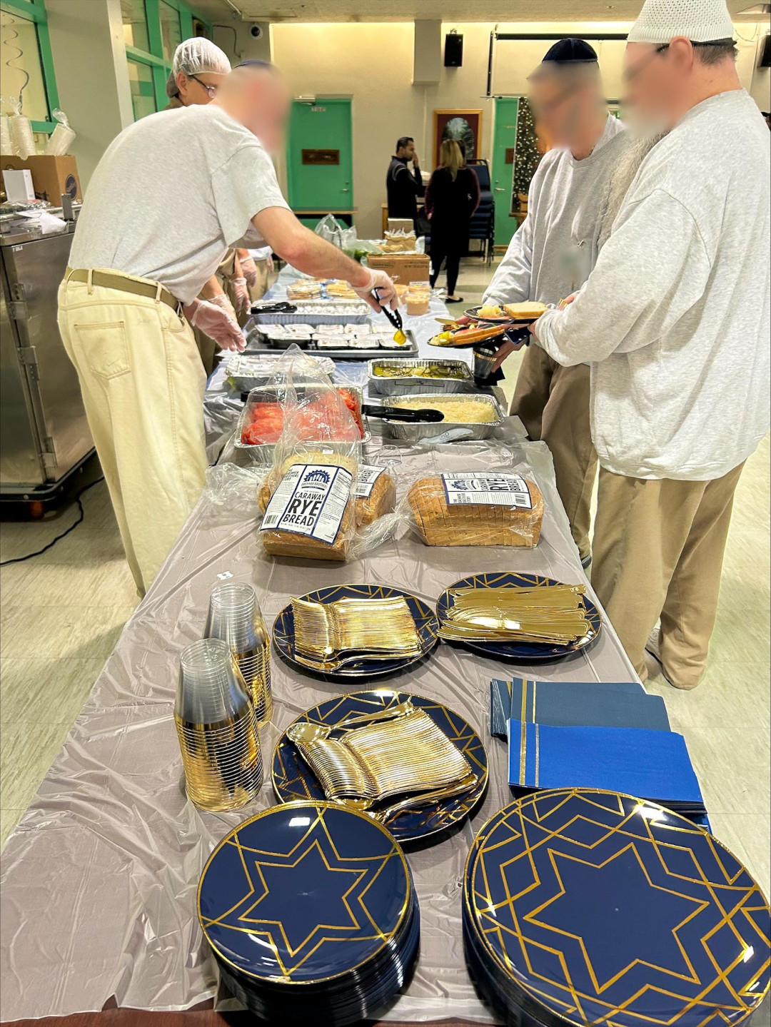 Three men serving themselves food at a buffet style line.