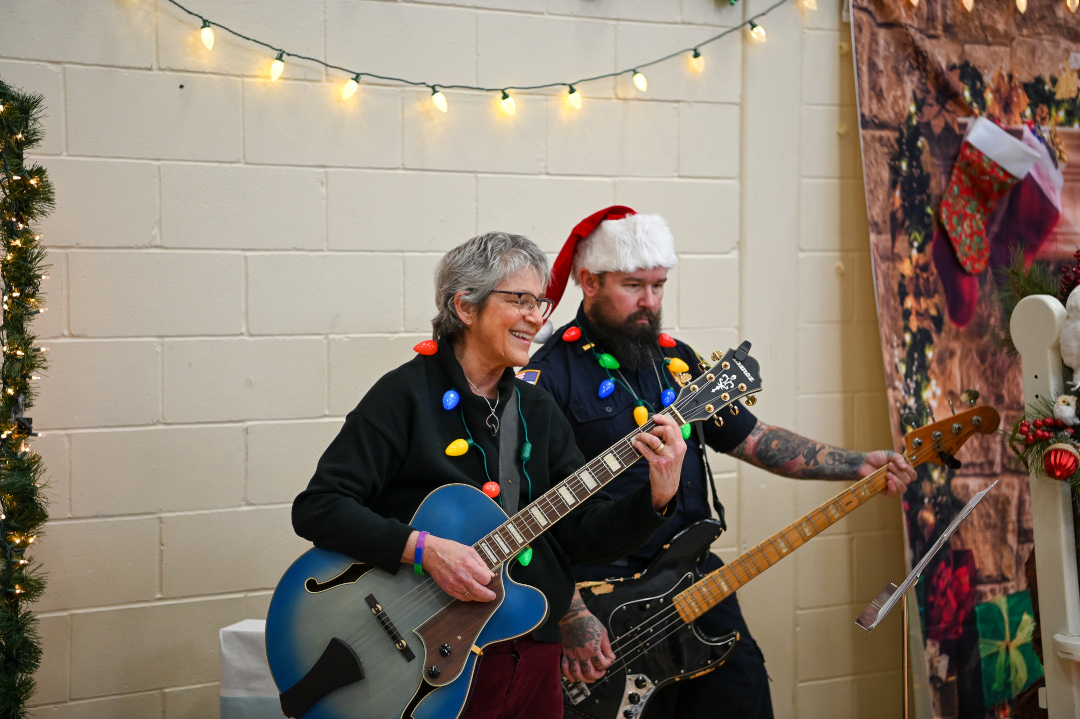 two people play guitar while wearing christmas lights and a santa hat